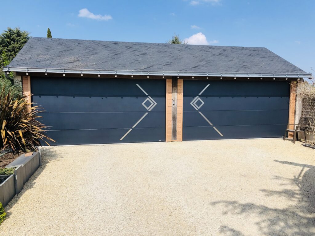 Porte de garage sectionnelle à design contemporain, avec motif géométrique sur façade de dépendance moderne.
