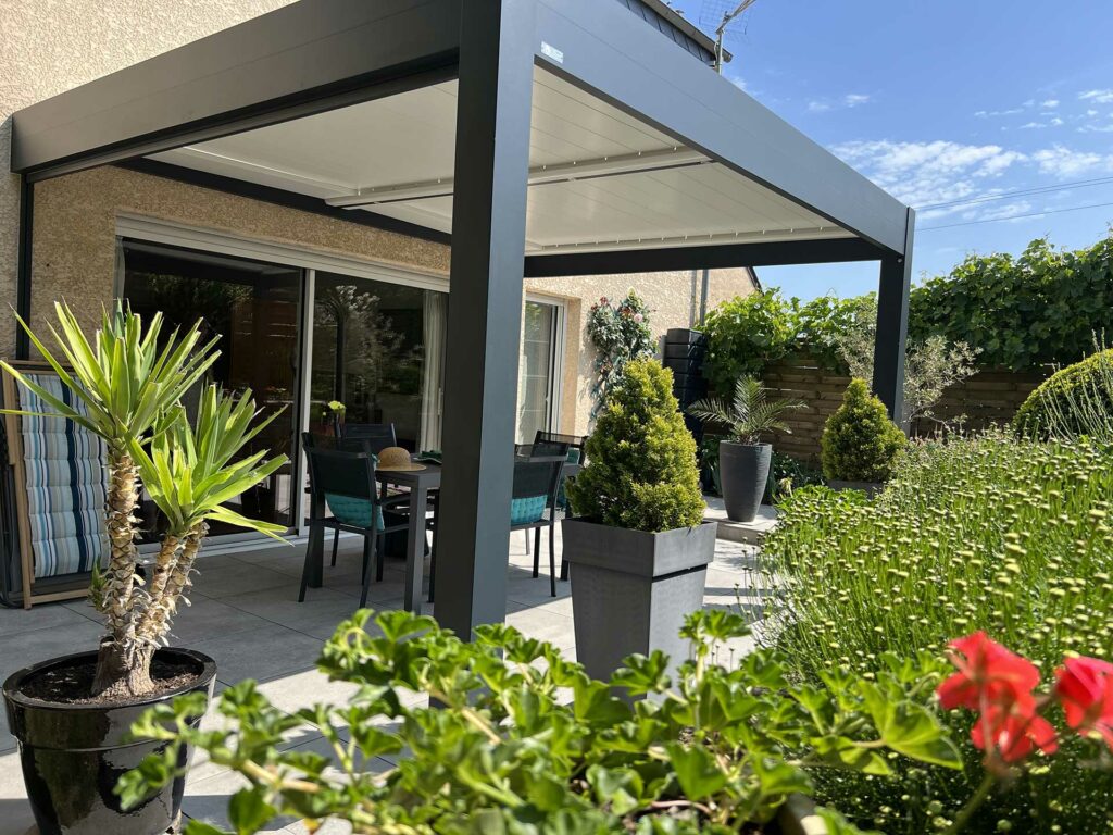 Salon de jardin installé sous une pergola bioclimatique 4x3 sur terrasse en bois