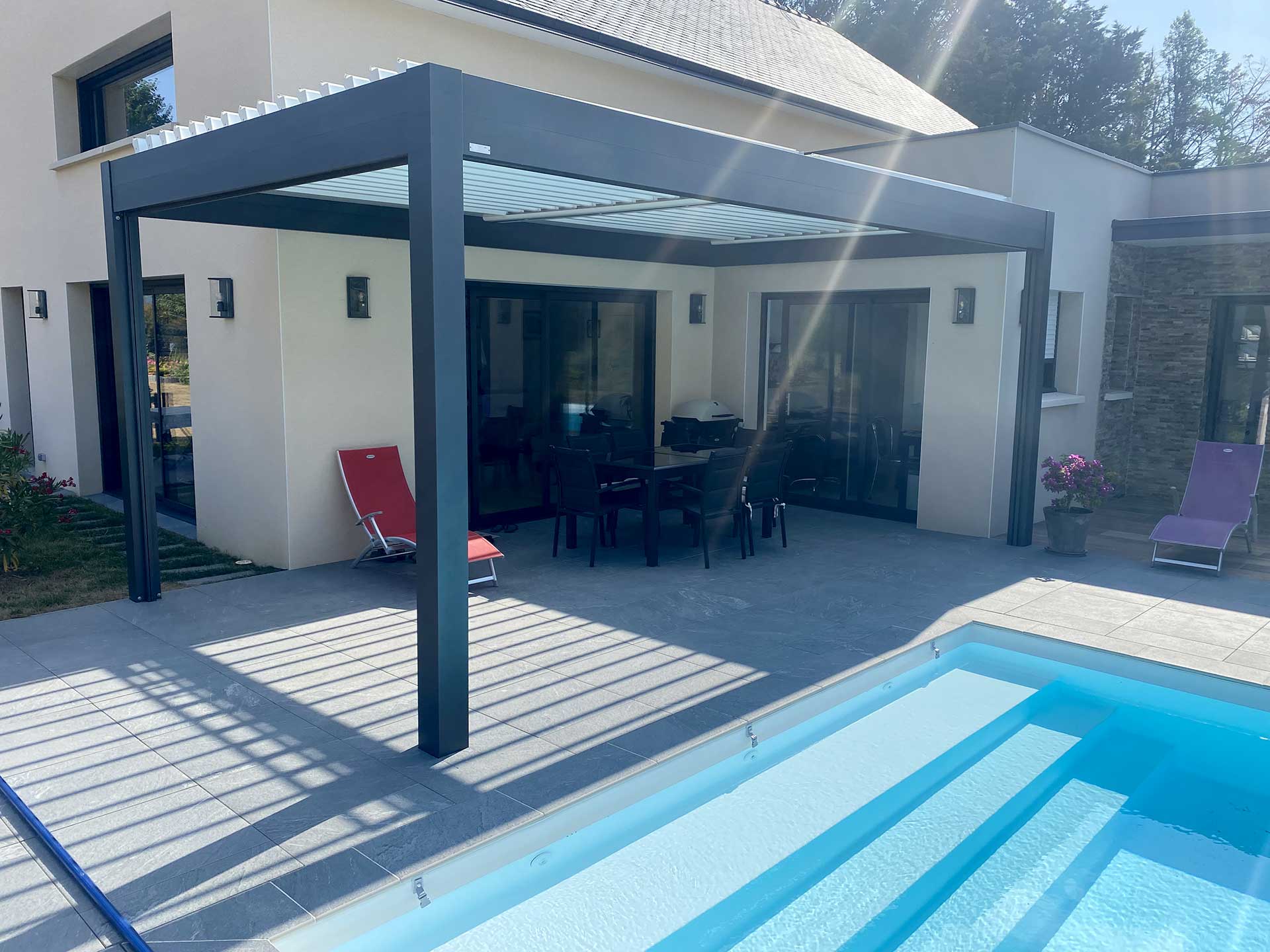 Pergola bioclimatique 4x3 moderne installée sur terrasse avec piscine et mobilier de jardin