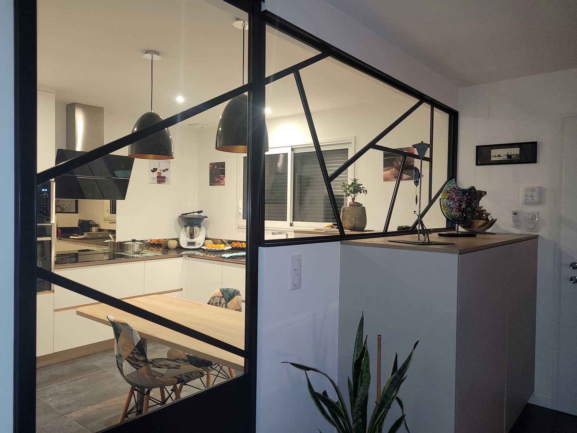 Verrière intérieure noire sur mesure avec motifs géométriques, séparation entre une cuisine moderne et un espace salon