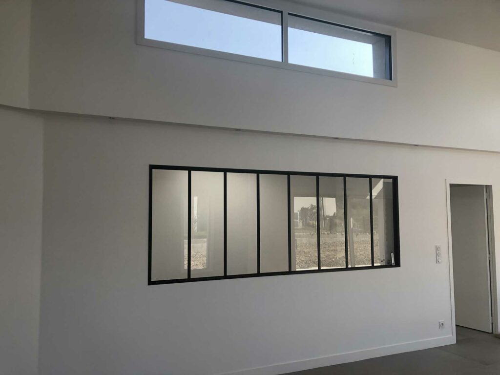 Verrière murale intérieure noire avec montants verticaux dans une chambre lumineuse