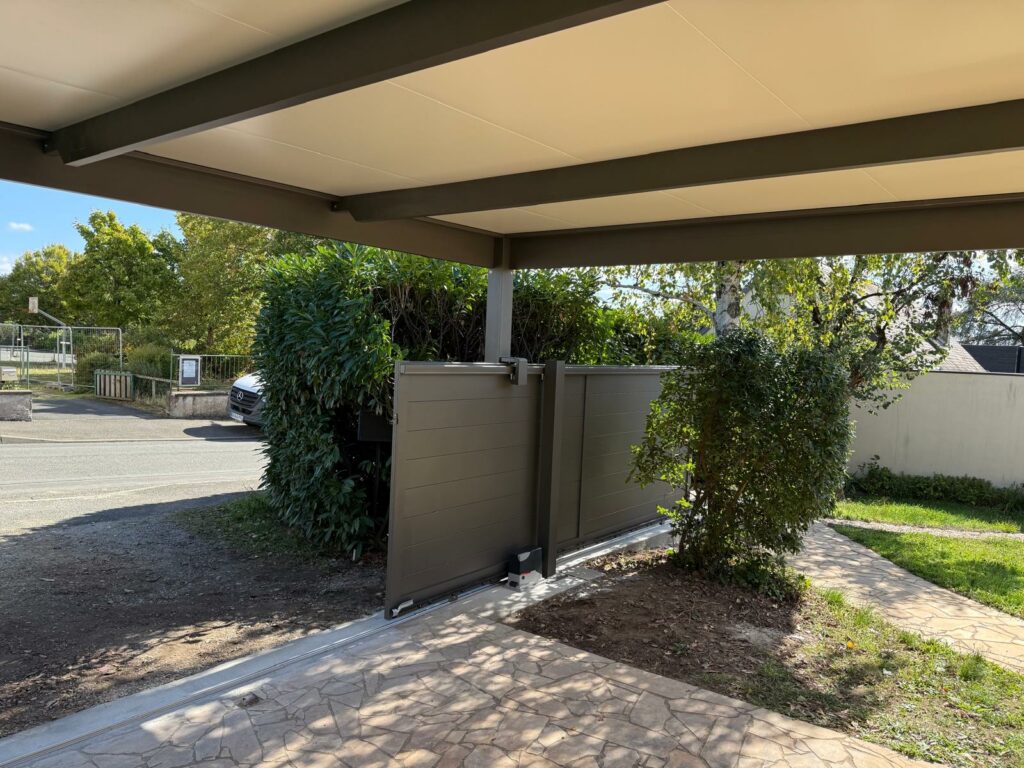 Portail coulissant aluminium plein marron motorisé sous carport, réalisation Levron Menuiserie dans le 49