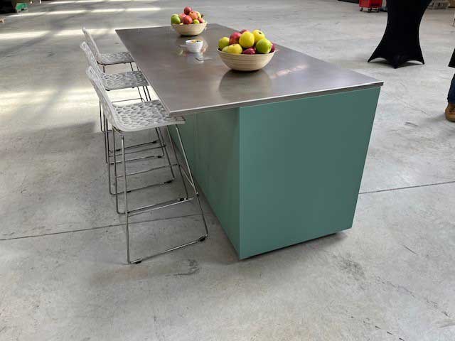 Ilot central de cuisine extérieure en aluminium vert avec plateau inox et tabourets hauts, style convivial