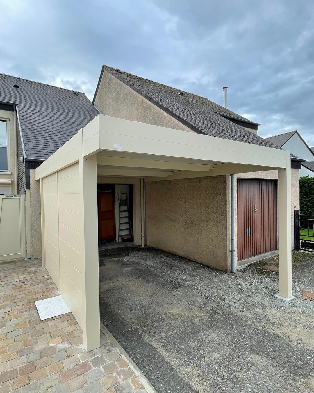 Carport aluminium dans le prolongement d’une maison rénovée, avec cloison latérale Carport aluminium dans le prolongement d'une maison rénovée, avec cloison latérale